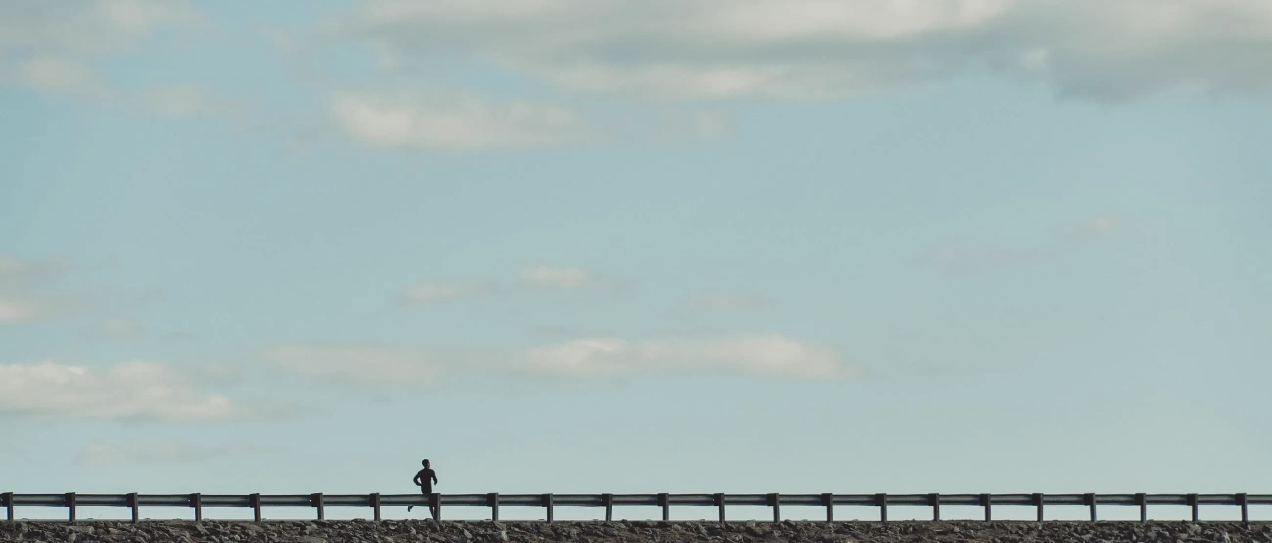 A lone runner on the horizon under a wide, clear sky