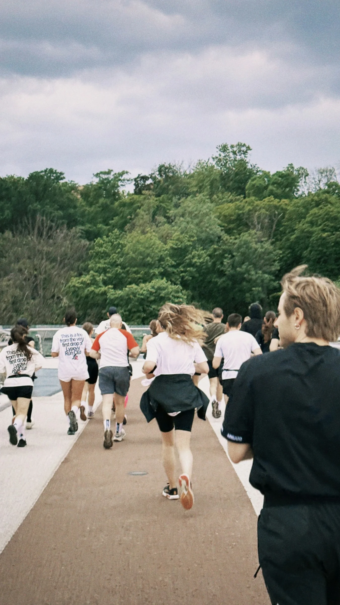 A group of runners spread along a tree lined path